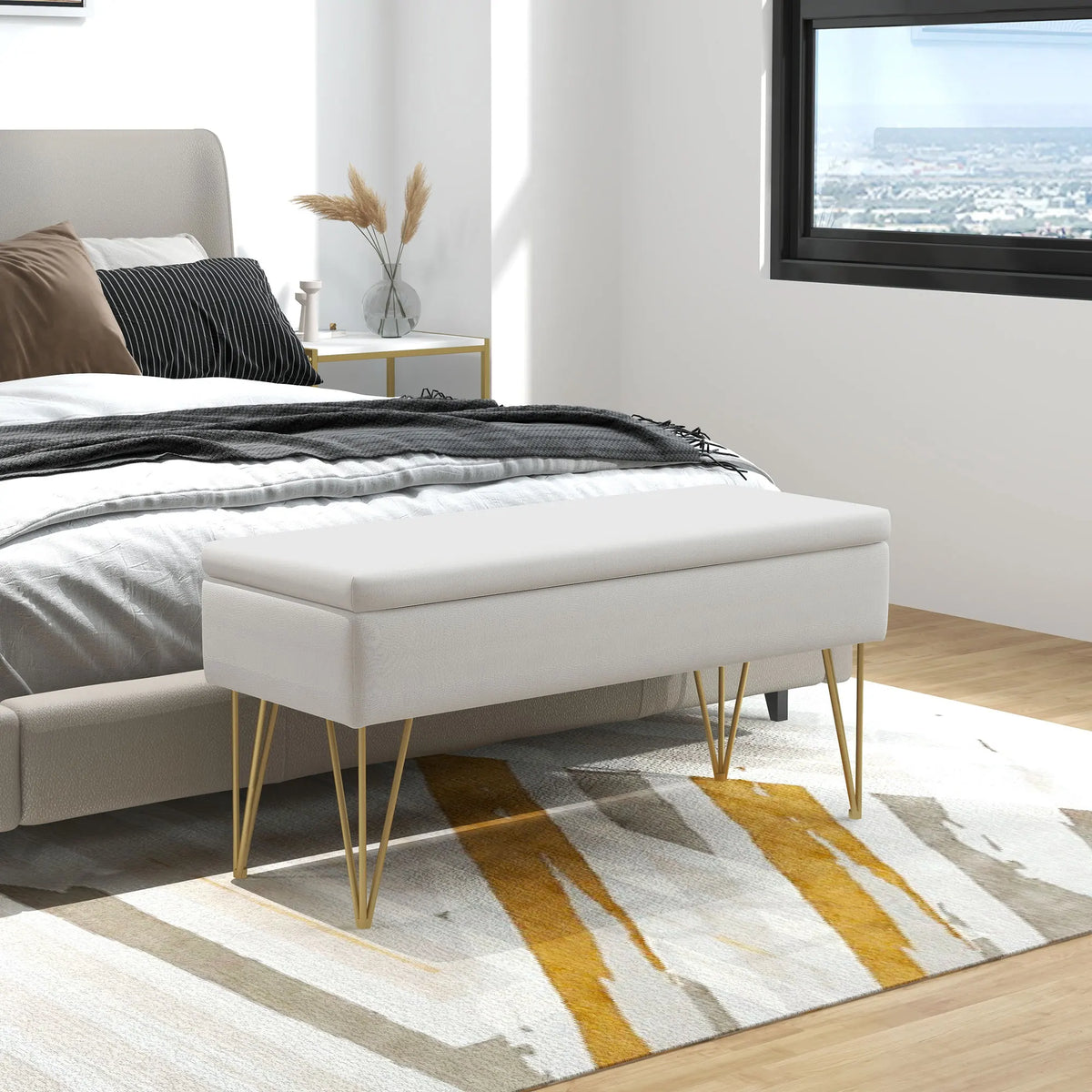 Banquette coffre blanche à pieds dorés, au bout du lit dans une chambre