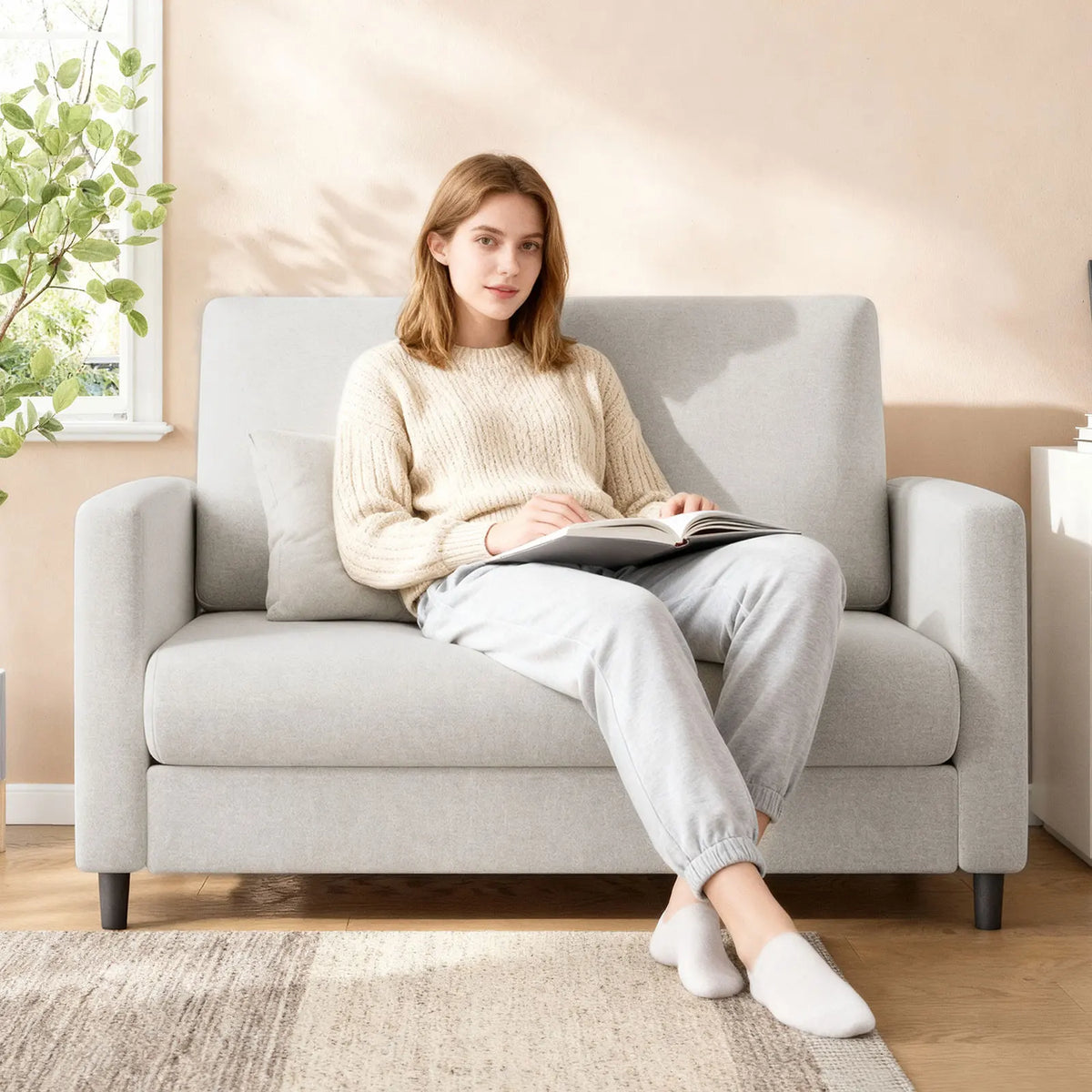 Canapé compact beige avec coussins lombaires, en situation avec une personne