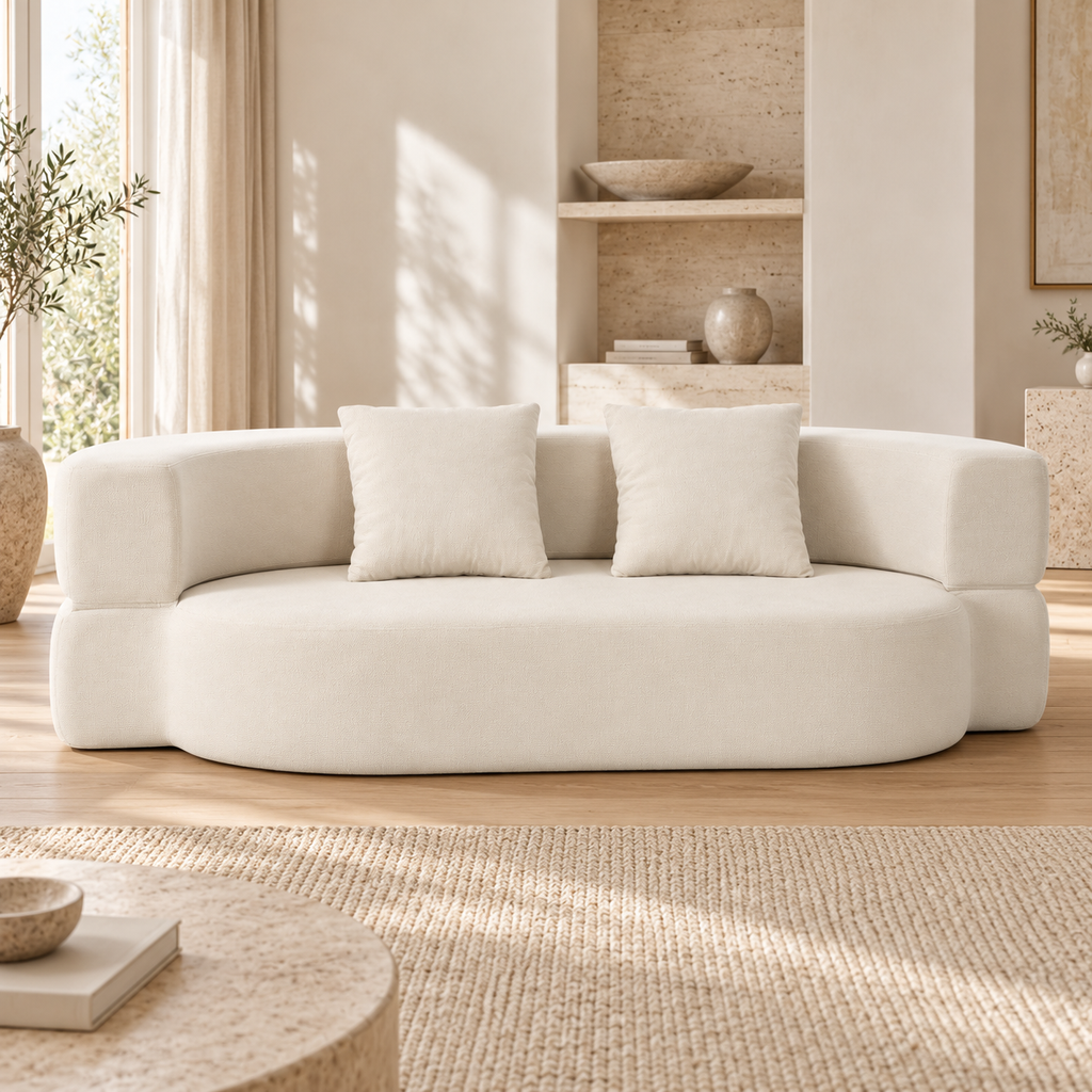 Canapé convertible arrondi beige avec deux coussins, position assise, autre angle dans un salon lumineux