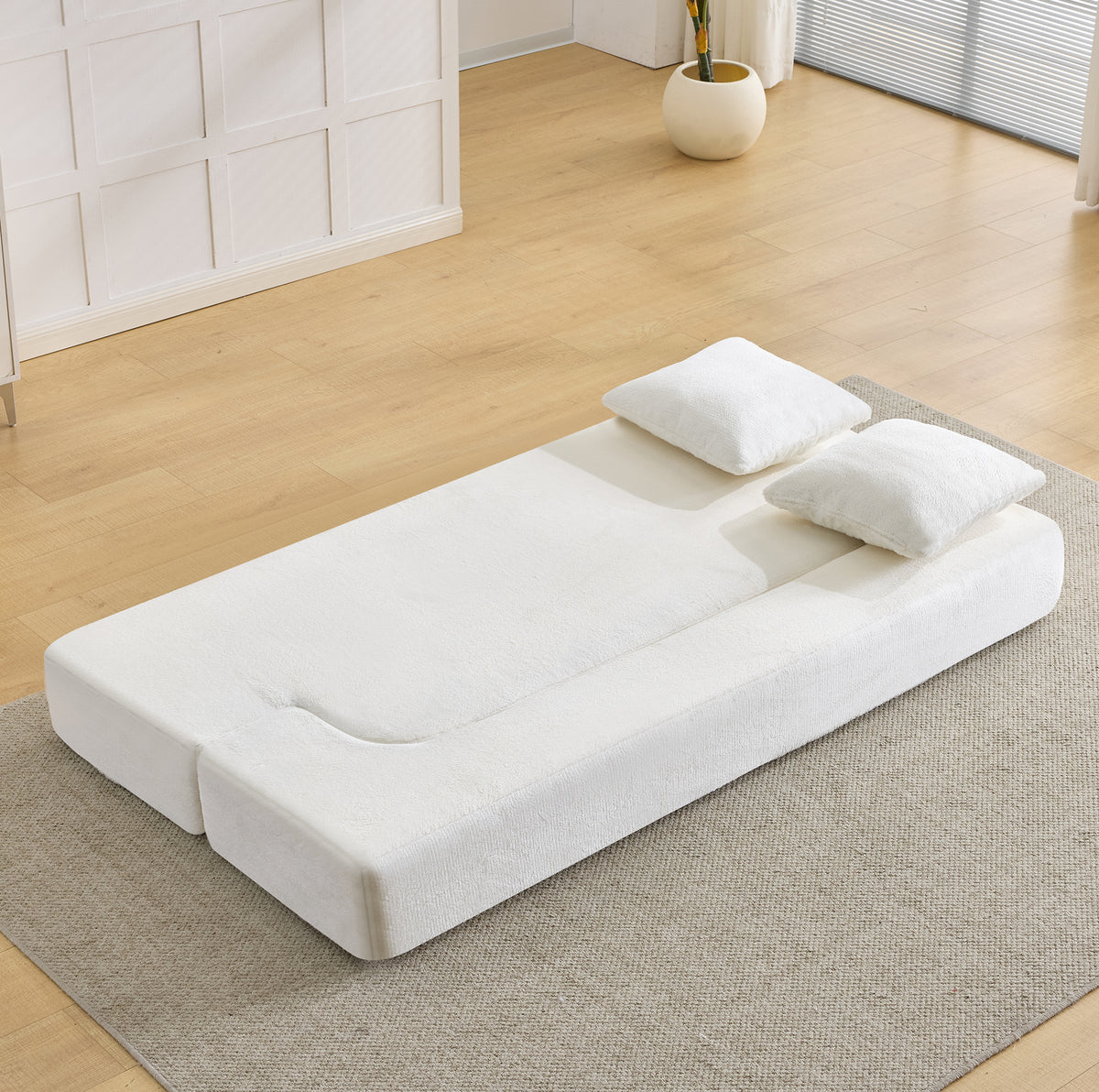 Canapé convertible pliable blanc crème, déplié en couchage dans un salon