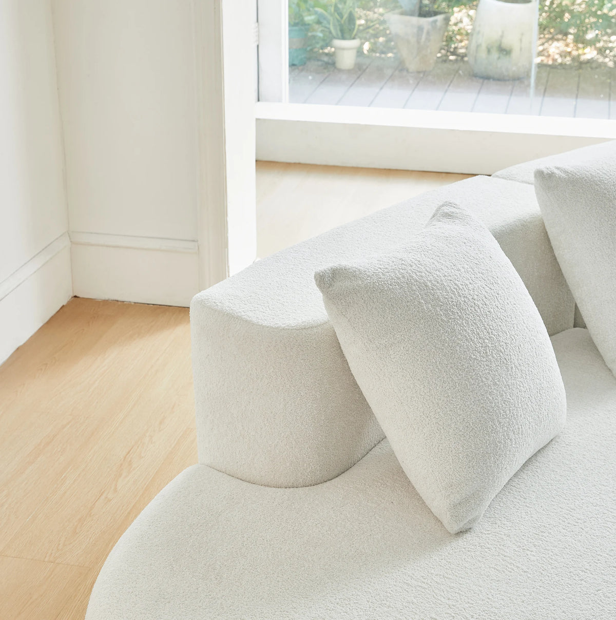 Canapé d’angle incurvé crème en tissu bouclé, détail de l’accoudoir et du coussin