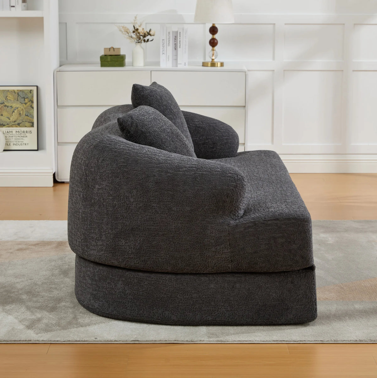 Canapé-lit arrondi en chenille gris foncé de 157 cm, fermé, vue de profil dans un salon