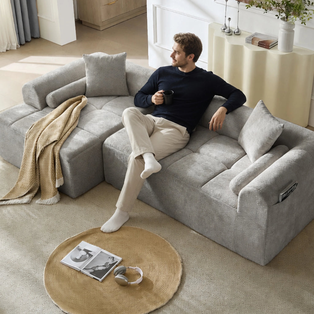 Canapé modulable en chenille grise, assise utilisée dans un salon