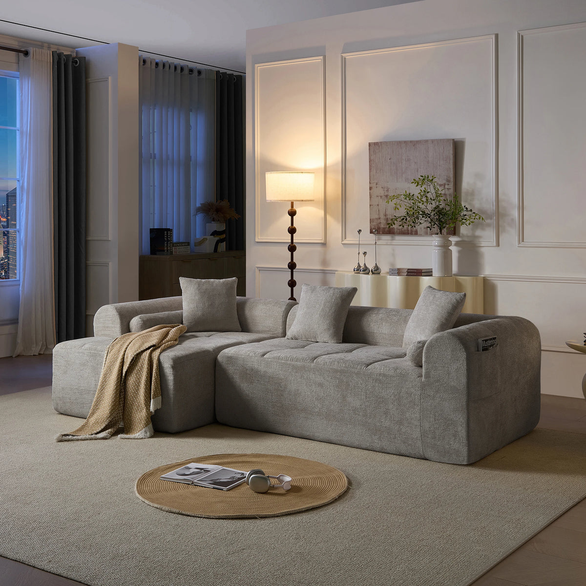 Canapé modulable en chenille grise, dans un salon en soirée
