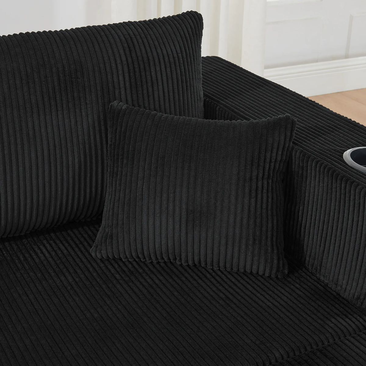 Canapé modulaire noir en velours côtelé à poufs mobiles, détail des coussins et du tissu côtelé