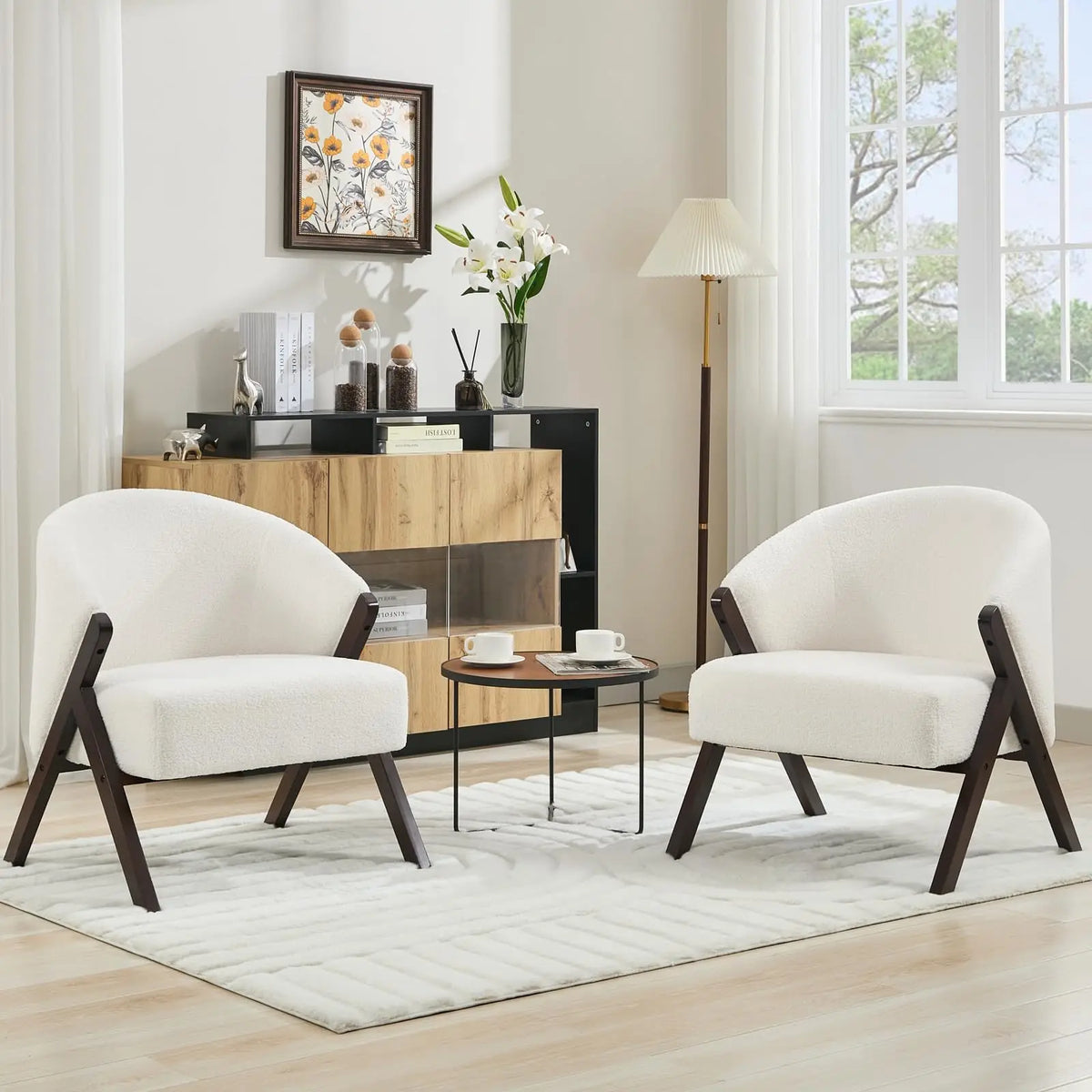 Fauteuil blanc en tissu bouclé à structure en bois foncé, deux exemplaires présentés dans un salon