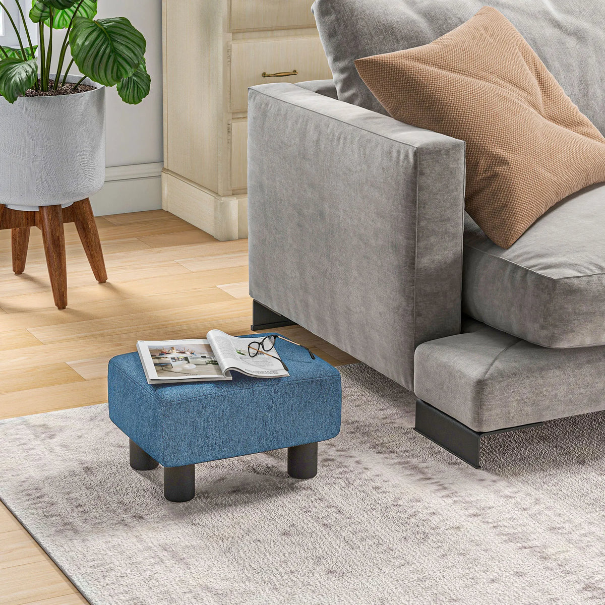 Pouf bleu à pieds en bois, dans un salon avec canapé en décor