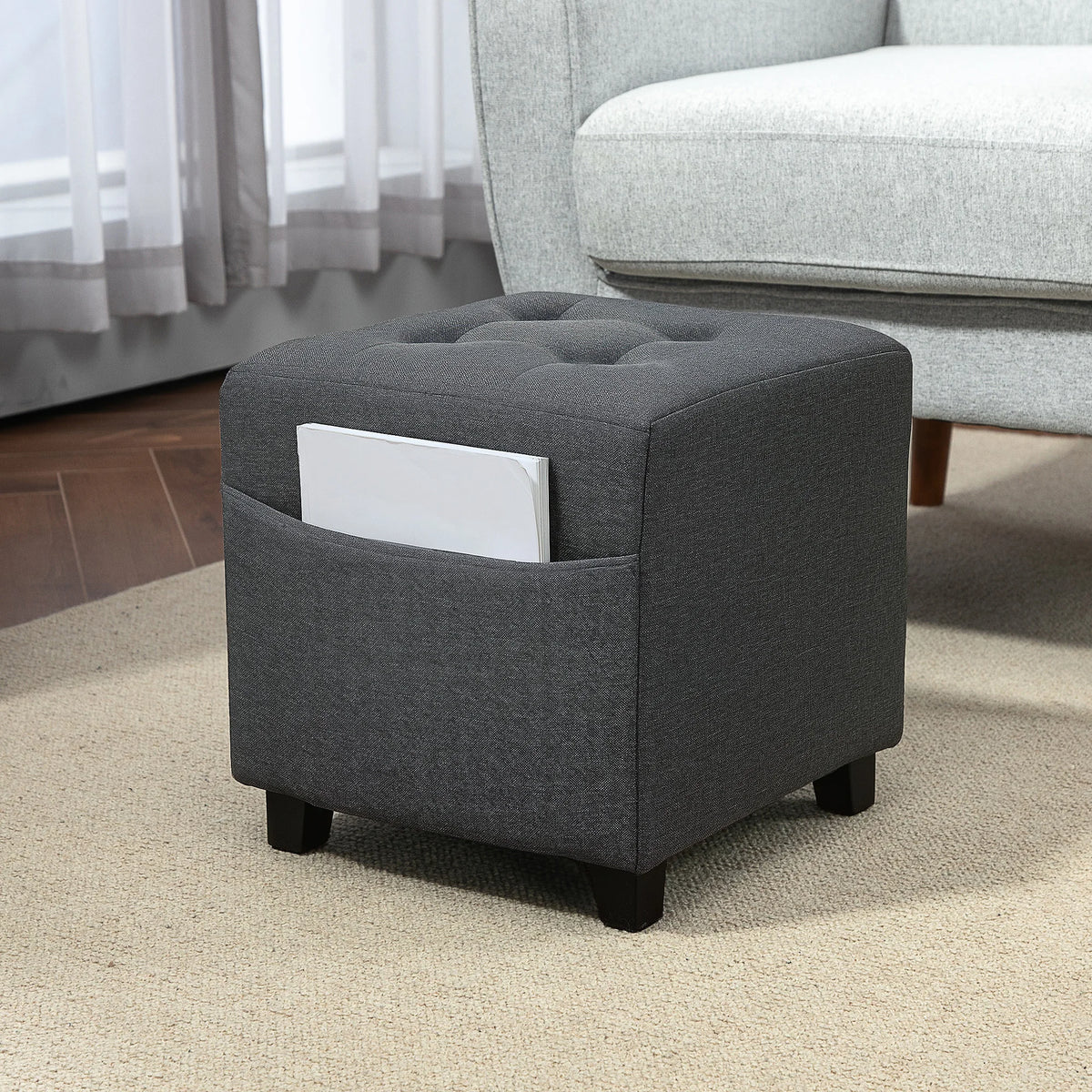 Pouf repose-pieds gris à poche latérale, dans un salon avec la poche latérale visible